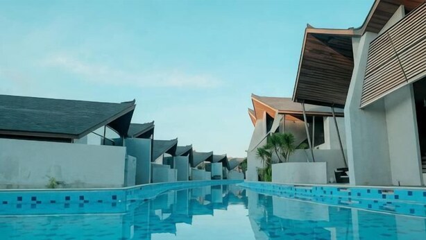 A swimming pool with a tiled edge, modern buildings with flat roofs, and a clear sky. - The Lavana Akatara Villa Nusa Dua (Bali)