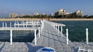 Een pier die het water in reikt, met een helder uitzicht op het strand en gebouwen op de achtergrond.