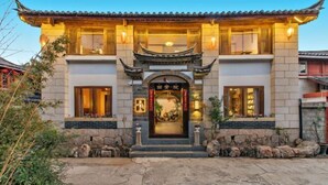 Een traditioneel Chinees gebouw met een betegeld dak, een centrale ingang met een decoratieve boog en stenen trappen die naar de deur leiden.