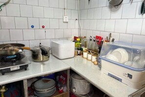 Une cuisine équipée d’une cuisinière, d’un appareil électroménager blanc et d’un récipient en plastique contenant de la vaisselle.
