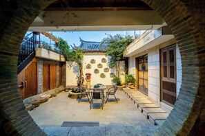 Une cour dotée d’un toit de style chinois traditionnel, une table avec des chaises et un chemin de pierre.
