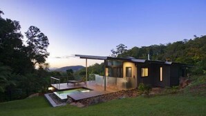 Et moderne hus med en veranda med glas og en swimmingpool.