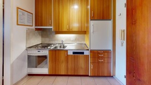 A compact kitchen with wooden cabinets, a stainless steel sink, a built-in oven, and a refrigerator. - Well-kept holiday apartament house in a prime location in St. (St. Moritz)