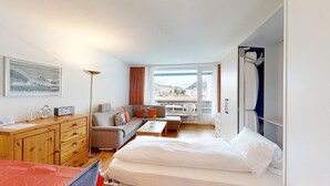 A hotel room with a bed, sofa, desk, and a view of the outside. - Well-kept holiday apartament house in a prime location in St. (St. Moritz)