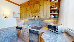 Een keuken met houten kastjes, een granieten aanrecht, een vaatwasser, een magnetron en een spoelbak.