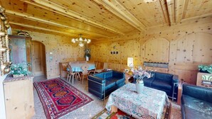 Een houten interieur met een eettafel, blauwe banken en een kamerkleed met patroon.