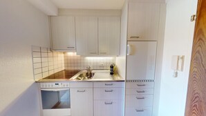 A compact kitchen with white cabinets, a stainless steel sink, and a built-in oven. - Well-kept holiday apartament house in a prime location in St. (St. Moritz)