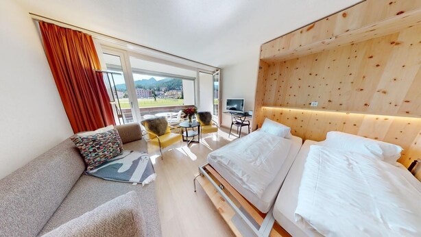 A modern hotel room with a bed, sofa, and desk area. - Well-kept holiday apartament house in a prime location in St. (St. Moritz)
