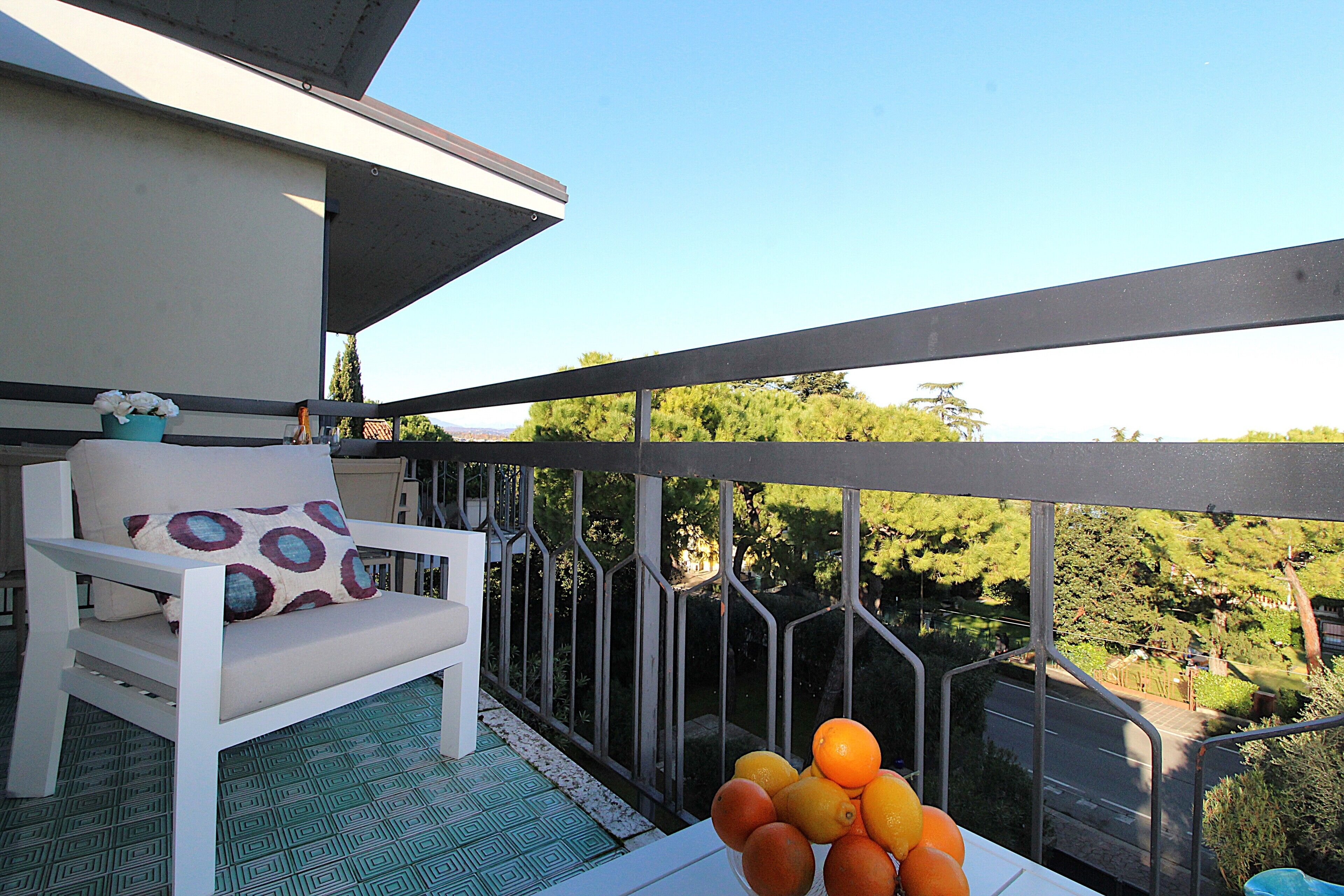 A balcony with a white chair and a table with oranges and lemons.