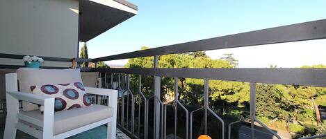 A balcony with a white chair and a table with oranges and lemons.