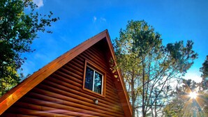Une cabane en rondins avec une entrée pavée de pierres, une porte blanche et une fenêtre.