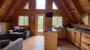 Un chalet confortable avec un plafond de style industriel, un îlot central dans la cuisine et un canapé dans l’espace de vie.