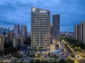 A modern hotel with a prominent 'C+' sign, surrounded by high-rise buildings and a busy urban street. - SSAW Boutique Hotel Foshan Qiandeng Lake (Foshan)