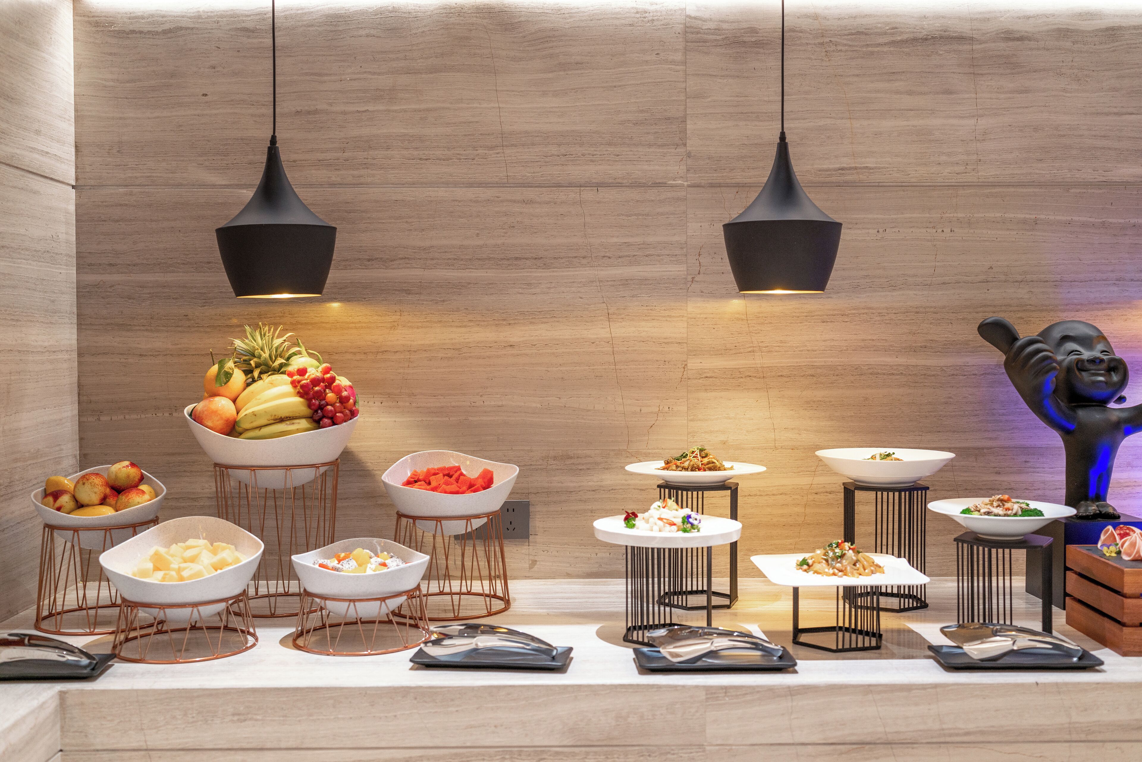 Mesa de buffet con diversos alimentos y una estatua de Buda.