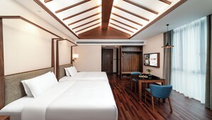 Habitación de hotel con una cama grande, un escritorio y una silla. Cuenta con una ventana con cortinas y un techo con vigas de madera.