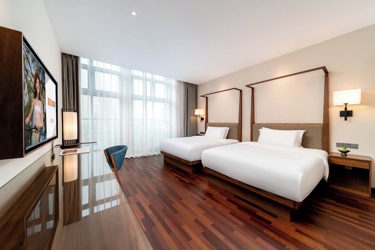 A hotel room with two beds, a desk, and a chair.
