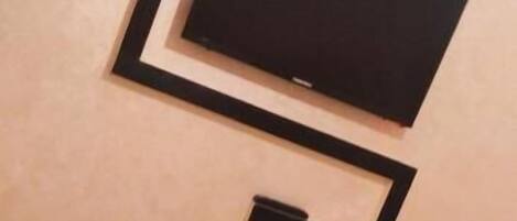A wall with a black rectangular object, possibly a television or screen, and a smaller black object below it.