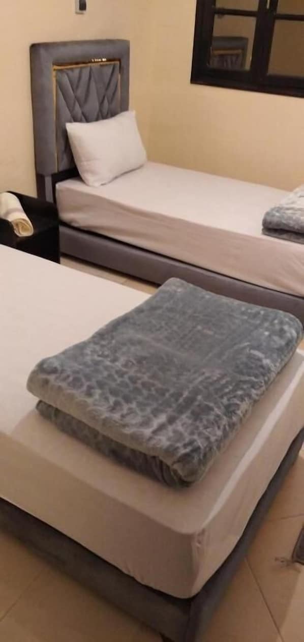 A double bed with a headboard and a pillow, a bedside table with a lamp, and a window with a view. - Hotel La Coline (Beni Mellal)