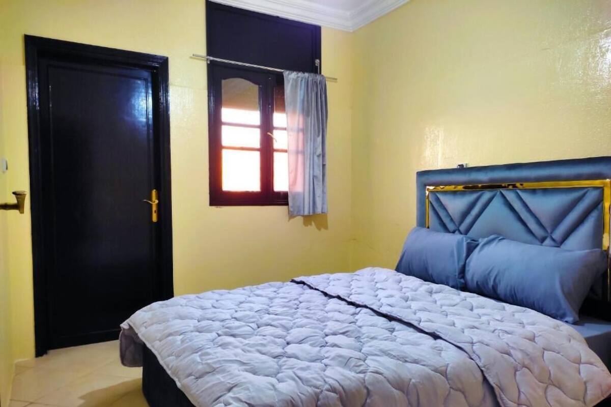 A bedroom with a bed, a window with curtains, and a door.