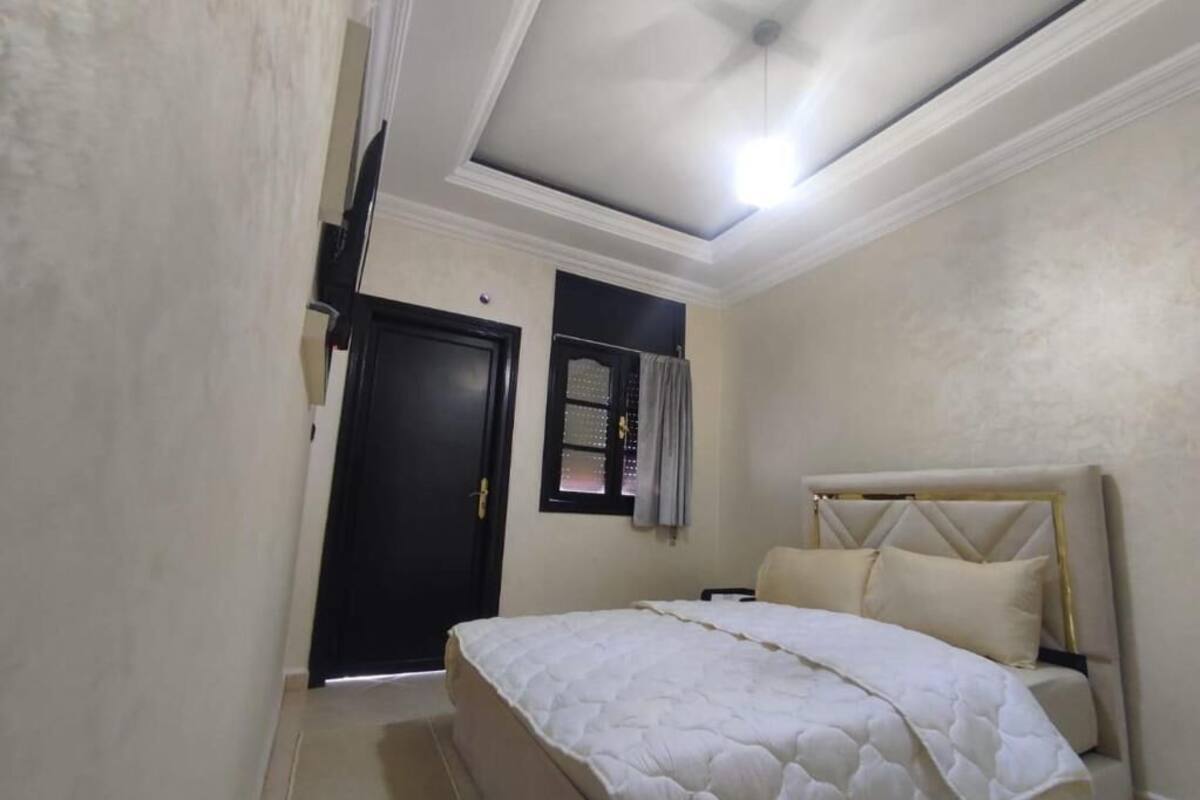 A bedroom with a bed, a window with curtains, a door, and a ceiling fan.