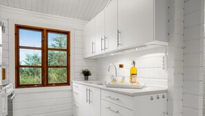 Une cuisine moderne avec des meubles blancs, une fenêtre en bois et un évier en acier inoxydable.