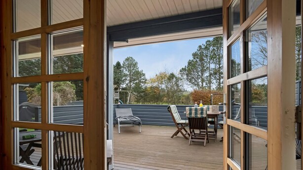 Une terrasse extérieure couverte, équipée d’une table et de chaises, d’un barbecue et d’une balançoire.