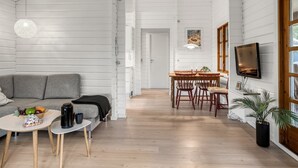 Un salon moderne avec un canapé gris, une table basse et un coin repas comprenant des chaises et une table en bois.
