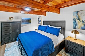 A bedroom with a bed, nightstands, a dresser, and artwork on the walls.