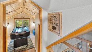 Una stanza con tavolo da biliardo, soffitto in legno e un cartello con la scritta 'Non svegliare l'orso'.