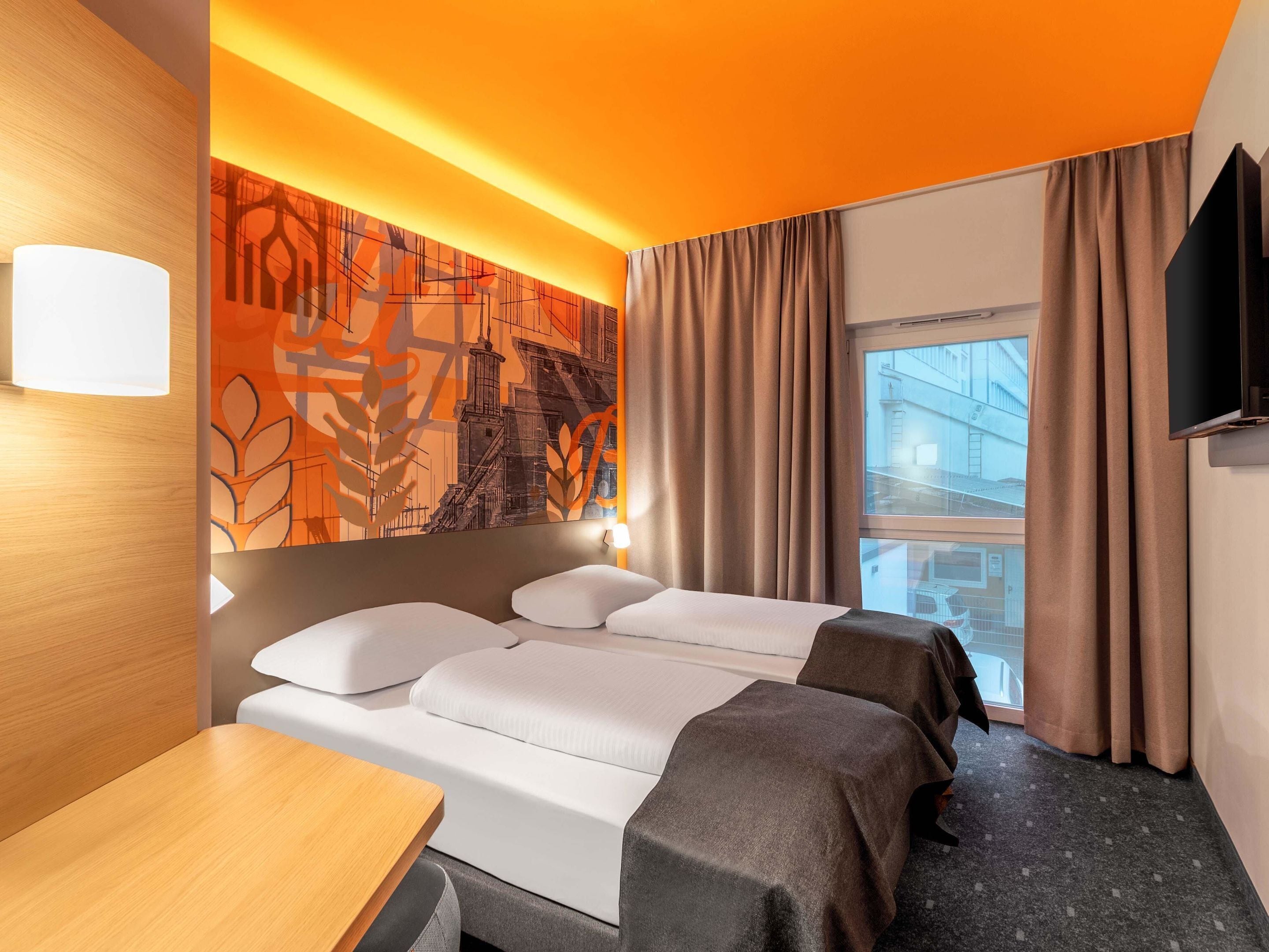 Ein Hotelzimmer mit Bett, Schreibtisch und einem großen Fenster.