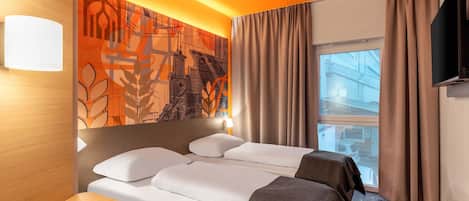 A hotel room with a bed, a desk, and a large window.