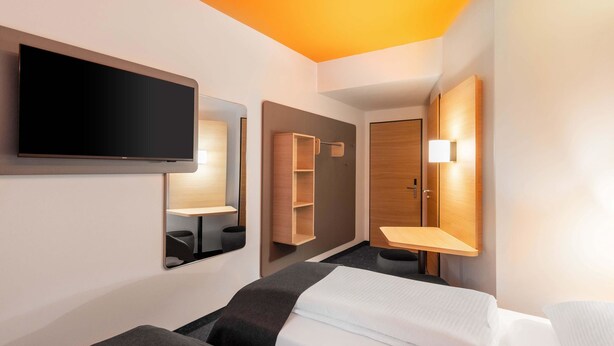 Una habitación de hotel con dos camas, televisión, espejo y armario.