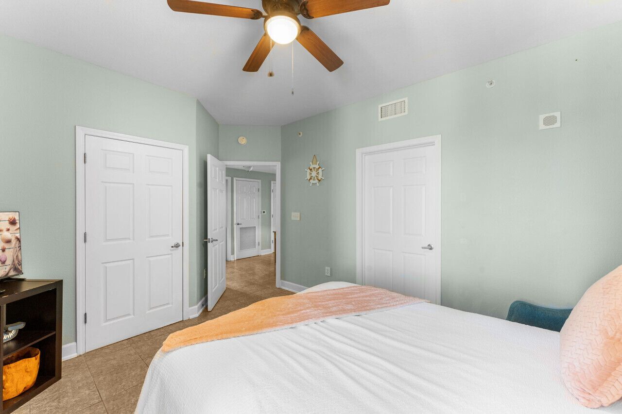 Un dormitorio con cama, ventilador de techo y un pasillo que conduce a otra habitación.