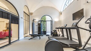 Una palestra con tapis roulant, macchinari per pesi e una panca.