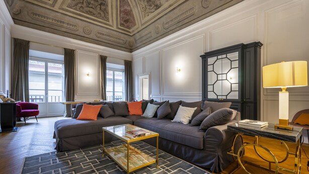 Un ampio soggiorno con un divano componibile, un tavolino in vetro e una lampada decorativa.