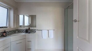A modern bathroom with a glass shower, white cabinets, and a large mirror. - Cosy and Comfortable Unit with Parking & Wifi (Devonport)
