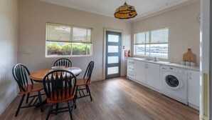 A compact kitchen with a dining area, a washing machine, and a view through the windows. - Cosy and Comfortable Unit with Parking & Wifi (Devonport)