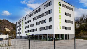 Een modern hotelgebouw met meerdere verdiepingen, grote ramen en een opvallend logo op de gevel.