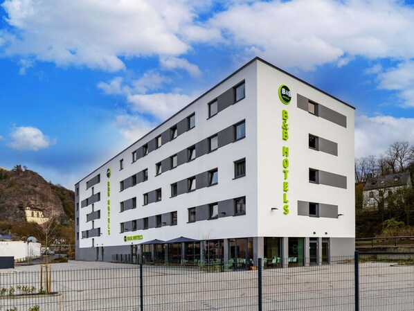 A modern hotel building with multiple floors, large windows, and a prominent logo on the facade. - B&B HOTEL Idar-Oberstein (Idar-Oberstein)