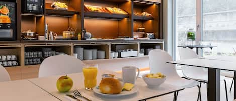 Un moderno comedor con buffet, mesas de desayuno y vistas al exterior.