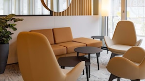 Een moderne zithoek met een bank, twee fauteuils, een bijzettafeltje en een potplant.