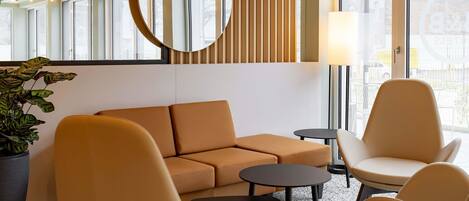 A modern lounge area with a sofa, two armchairs, a small table, and a potted plant.