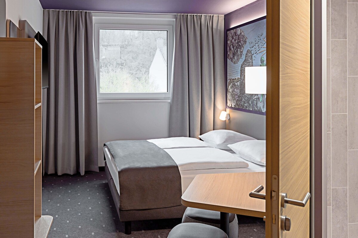 Hotellihuone, jossa on sänky, työpöytä ja ikkuna.