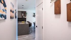 A modern kitchen with a dark countertop, wooden cabinets, and a dining area with chairs. - Modern 2 Bedroom Condo with Workspace (Revelstoke)