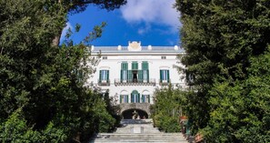 Stunning grand building with a central entrance and lush greenery surroundings.