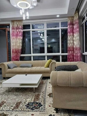 A living room with a beige sofa, a white coffee table, and a patterned rug. - Utawala Executive Residence (Nairobi)