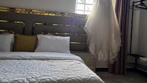 Une chambre à coucher avec un lit, une robe suspendue et une fenêtre.