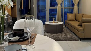 A modern living room with a dining area, featuring a round table, sofa, and a TV mounted on the wall.