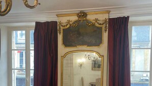 Une pièce avec une commode en bois, un grand miroir et des rideaux rouges.