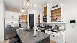 Una cocina moderna con armarios blancos, encimera de mármol y electrodomésticos de acero inoxidable.